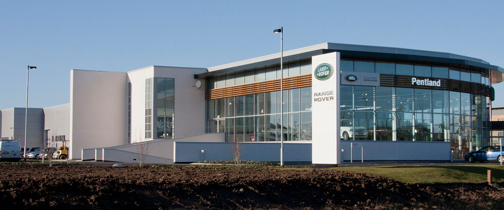 Modern car dealership exterior with large windows and brand logos